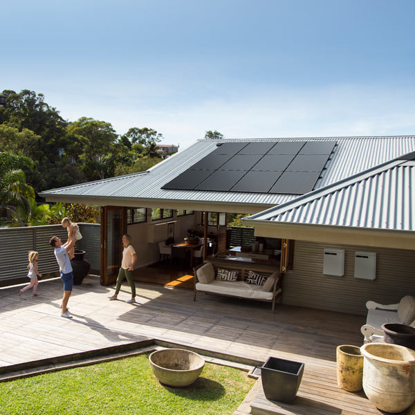 GoodWe Lynx home solar battery installed outside house with family playing nearby and solar panels on roof